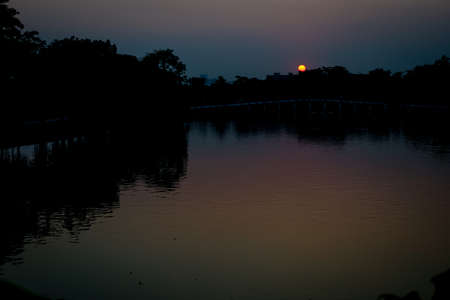Sunset at lake in Bangkok Thailand. With reflection of sky on surface of waterの写真素材