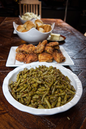 Looking down the spread of a fried chicken country dinner which includes southern green beans and fresh baked yeast rolls.の写真素材