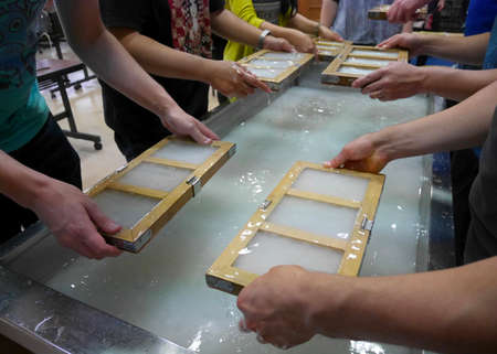 People creating paper as a Japanese handicraft by using some mold; pulp, and water