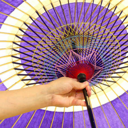 A hand holding a Washi paper umbrella or an umbrella made by Japanese paperの写真素材