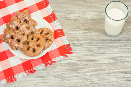 Photo of plate full of tasty cookies on checkered tablecloth and glass of milk on wooden tableの写真素材