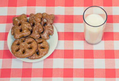 Plate with tasty cookies and glass of milk on checkered tableclothの写真素材