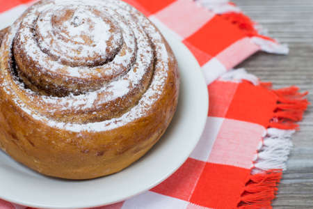 Close up photo of tasty cinnamon roll with powderede sugar on white plateの写真素材