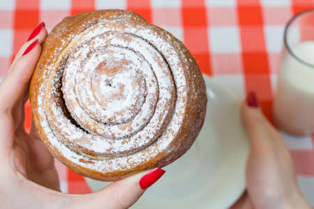 Close up picture of sweety tasty cinnamon roll in woman's handの写真素材