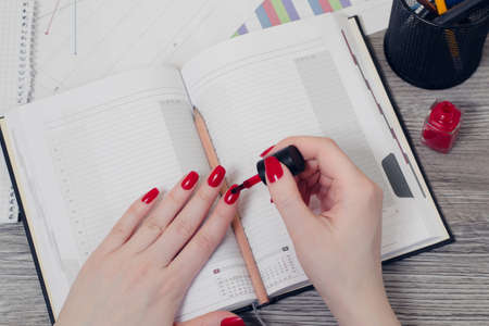 Close up overhead view  photo of woman's hands painting nails in red colorの写真素材