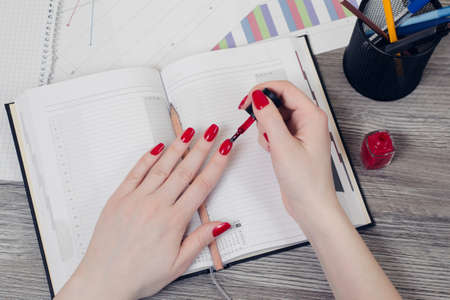 Close up top view picture of woman's hands painting nails at workplaceの写真素材