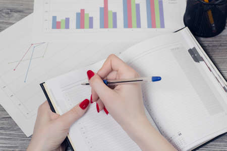 Close up top view photo of woman's hands writing useful information in notepadの写真素材