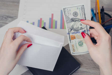 Concept of corruption at work. Woman's hand  putting money into an envelopeの写真素材