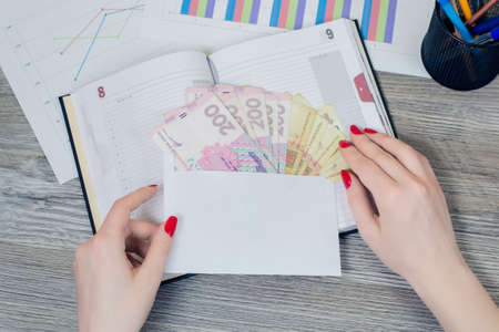 Close up top view photo of an envelope with Ukrainian money in it lying on desktopの写真素材