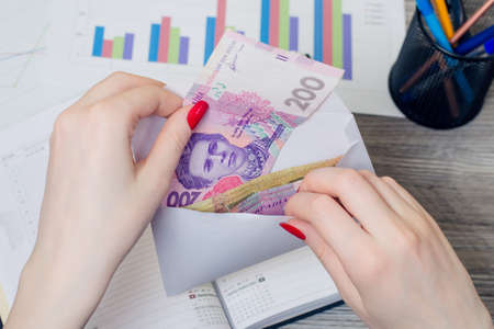 Woman's hands taking salary from an envelopeの写真素材