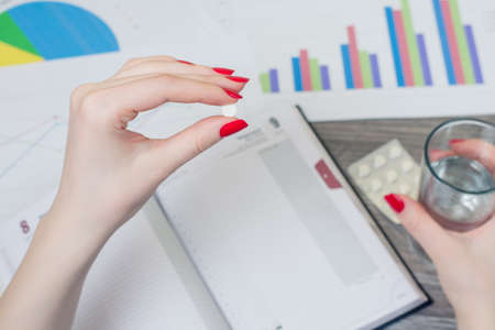Close up picture of woman's hand holding small pill and glass of water on the backgroundの写真素材