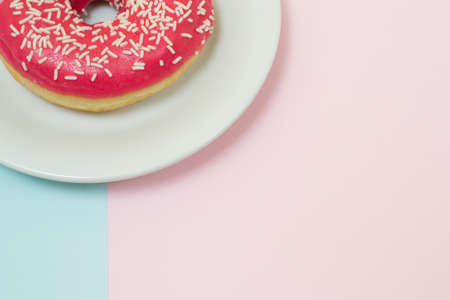Delicious tasty glazed bright pink donut on blue and pink background, top view, close up, minimal style, soft color, copyspaceの写真素材