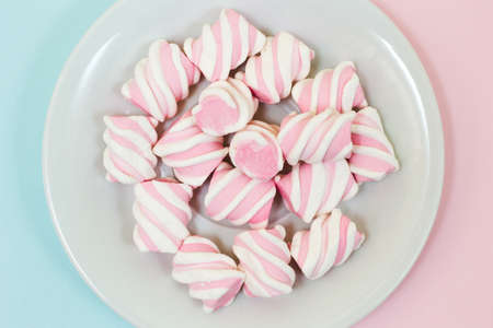 CLose up, top view photo of tasty yummy pink and white marsmallows on half blue half pink background. Minimal style, soft colorsの写真素材