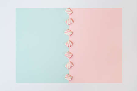 Top view photo of colorful line of marshmallows in the centre of half blue half pink background in white frameの写真素材