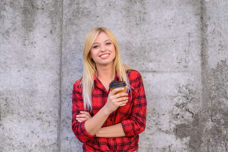 Smiling happy woman enjoying coffee. Portrait of happy woman in checkered red shirt holding cup of coffee.の写真素材