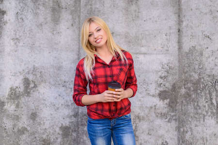 It's coffee time! Coffee time concept. Woman with beaming smile drinking coffee. Close up portrait, grey backgroundの写真素材