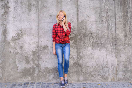 Young pretty woman talking on mobile phone while having a walk in a cityの写真素材