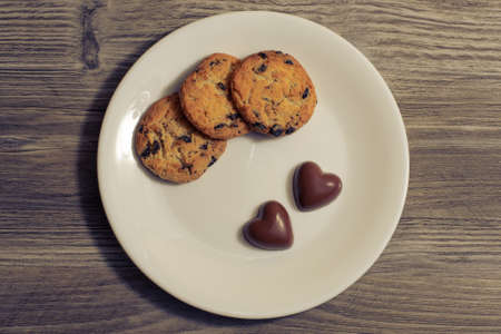 Valentine present gift romantic lovely candy homemade chocolate date breakfast snack concept. Top up overhead close up photo of a tasty sweet fresh cookies and candies in shape if heart on a wooden kitchen tableの写真素材