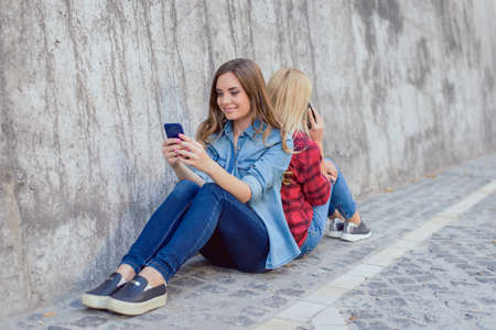 Sit texting cell call best age mobilephone watch play person people app store back-to-back concept. Cure beautiful pretty lovely girl reading media news on the internet using telephoneの写真素材