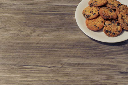 Top above overhead close up view photo of tasty yummy delicious crunchy crispy cookies with chocolate on whittle round plate isolated on a wooden table background copy-space. Place fot text.の写真素材
