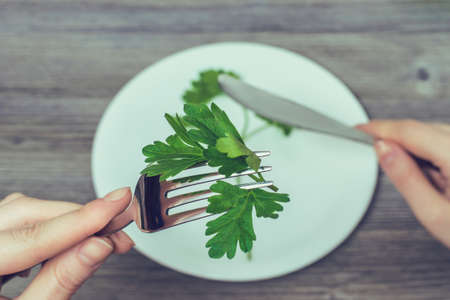 Close up photo of woman's hands holding parsley on forkの写真素材
