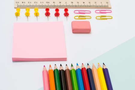 Set of school supplies. Top view close up photo of color pencils, stickers, paper clips and pins, rubber, ruler on white backgroundの写真素材