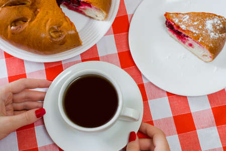 Overhead view photo of homemade cherry cake and cup of tea on checkered tableclothの写真素材