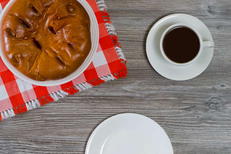 Overhead view photo of homemade cherry pie, cup of hot fresh tea and empty plate on wooden tableの写真素材