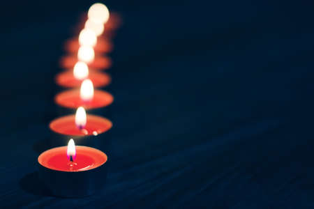 A row of candles on dark wooden backgroundの写真素材