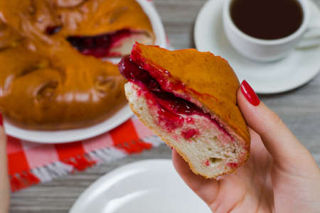 Close up photo of tasty yummy piece of cherry pie in woman's handの写真素材