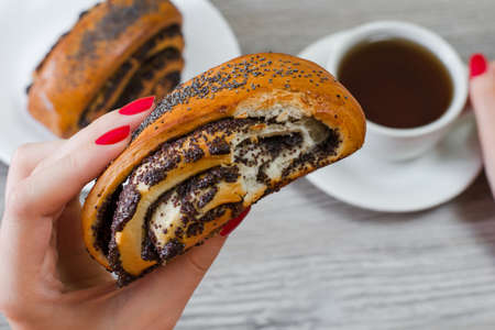 Close up photo of tasty bun rich in poppy seeds, cup of tea on the backgroundの写真素材