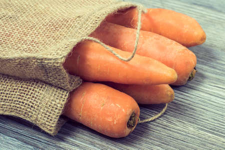 Close up photo of fresh carrots in bag on wooden tableの写真素材