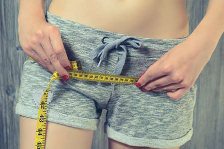 Woman measuring her hips using yellow tape measureの写真素材