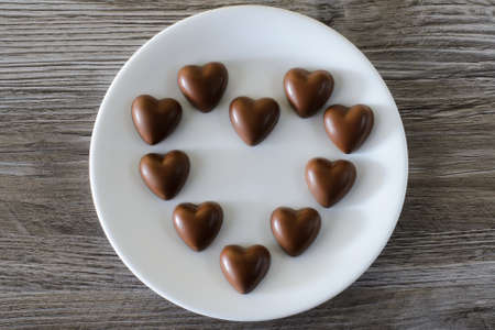 Holiday st valentine's day date. Top up overhead close up view photo of a tasty sweet yummy beautiful chocolate cxandies in shape of hearts on a wooden background tableの写真素材