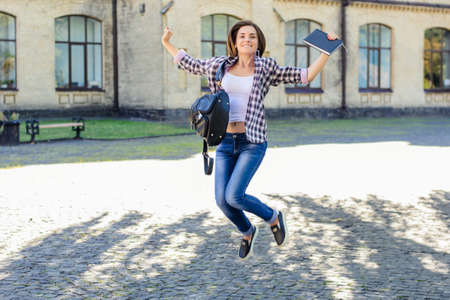 Happy smiling excited young female student jumping, celebrating and  triumphing because of entering the universityの写真素材