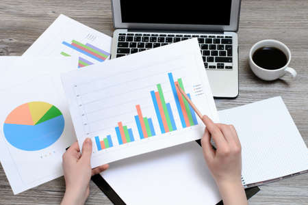 Concept of office workplace. Hands holding the results of sales represented on the graphicsの写真素材