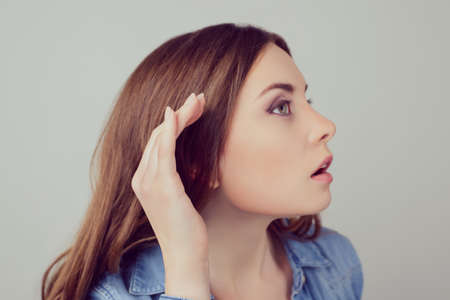 Close up portrait of interested nosy newsy beautiful woman wants to hear the latest news isolated on gray backgroundの写真素材