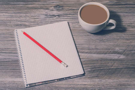 Background of open notebook, pencil and cup of hot coffee on the table, top view. Waiting for inspirationの写真素材