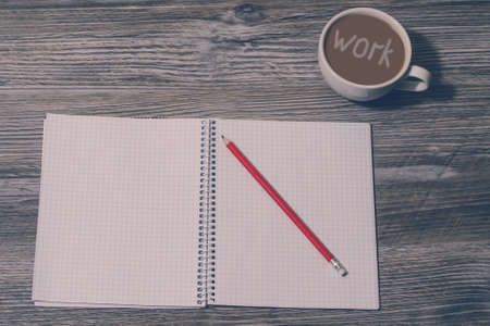 Open notebook, pencil, cup of coffee with inscription "work" on it on grey wooden background, top view. Tired after hard workの写真素材