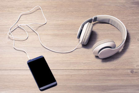 White headphones and mobile phone on a table の写真素材