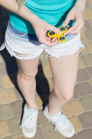 Young girl holding fidget spinner in hands while having a walk outdoorsの写真素材