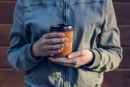 Young woman holding cup of fresh morning coffee against wooden backgroundの写真素材