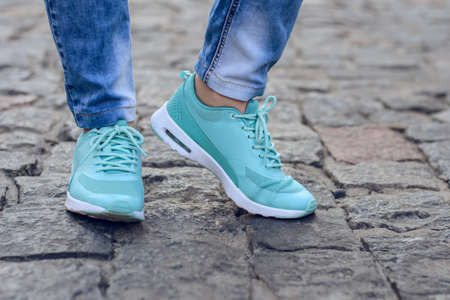 Photo of feet in new fashionable sneakers while having a walk in city