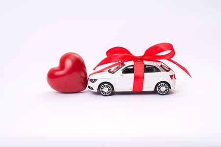 Close up profile side view photo of cute lovely sweet modern white toy car with red heart bow ribbon...