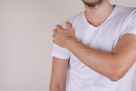 Therapy treatment ill concept. Sad upset stressed unhappy man touching shoulder isolated on gray grey background copy spaceの写真素材