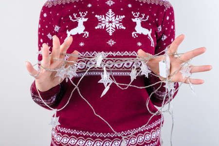 Cropped close up photo of angry sad upset crazy teenager's hands trying to untangle unravel christmas lights isolated on grey background copy spaceの写真素材