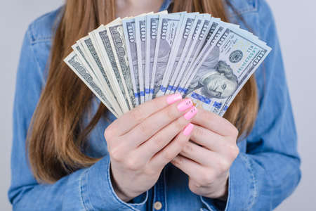Close-up cropped view photo portrait of cheerful happy lady economical lady showing advertising lot large many pile of money in hand isolated grey backgroundの写真素材