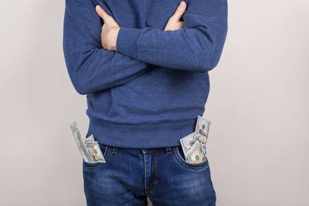 Cropped closeup photo portrait of satisfied cool handsome guy holding usa cash in pockets isolated grey backgroundの写真素材