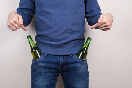 Do you like it concept. Cropped close-up photo of self-confident macho guy paying attantion on his two bottles in pockets isolated grey backgroundの写真素材