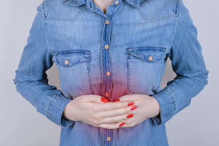 Digestion indigestion people person concept. Cropped close up photo of sad unhappy stressed depressed lady suffering from stomach-ache isolated on gray backgroundの写真素材
